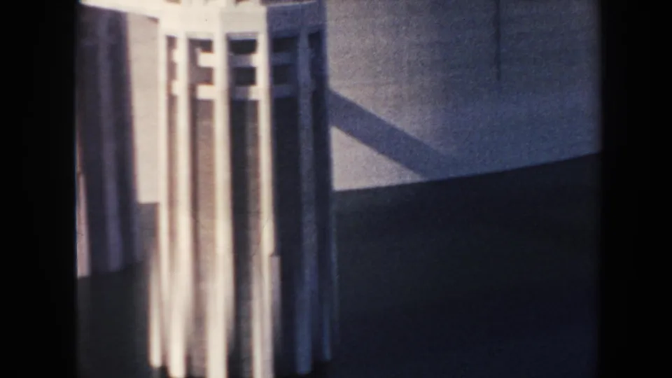 Handheld 8mm close-up of Hoover Dam tower columns and adjacent dark concrete surface, with strong contrast and film grain.