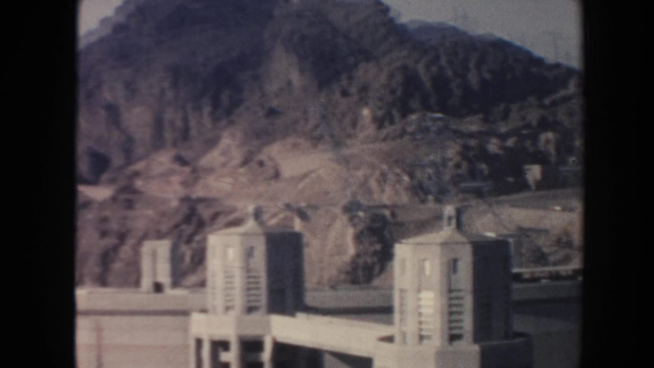 Dam towers and rocky cliffs appear across a reservoir area.