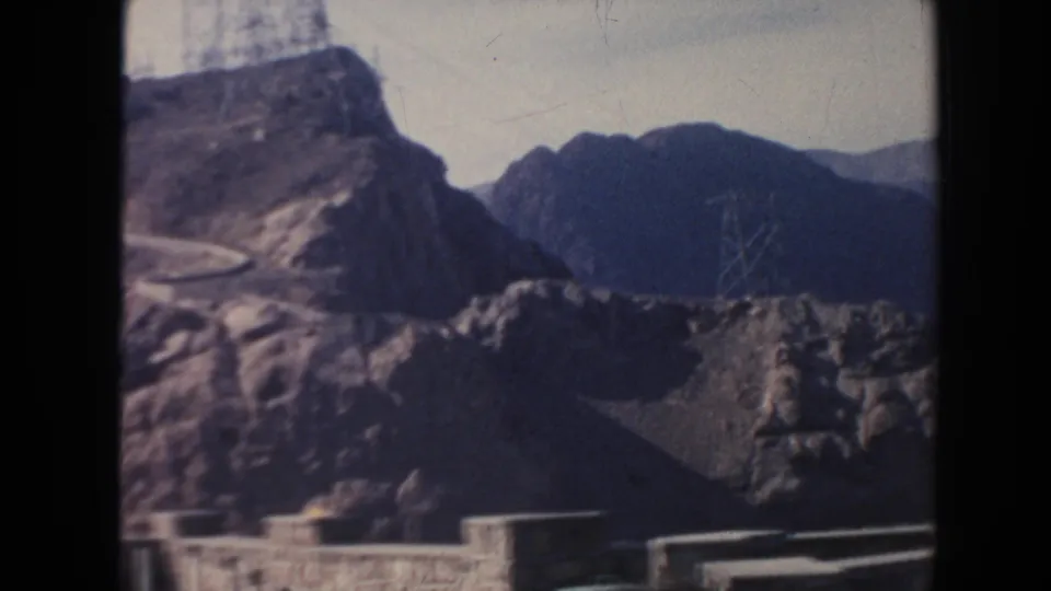 1962 Arizona footage showing a winding road through rocky terrain with power towers above the dam area.