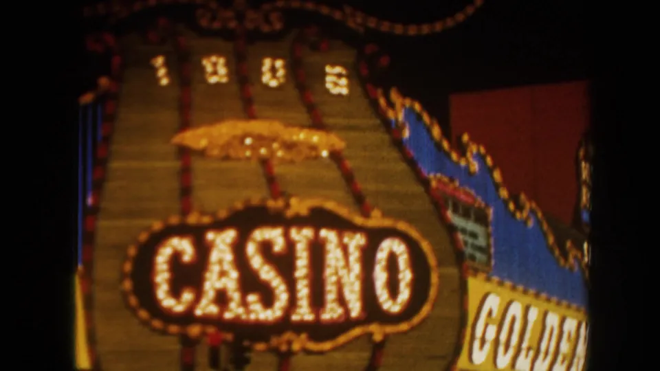 1962 8mm frame showing a large bulb-lit casino sign with partial Golden Nugget signage at the edge.