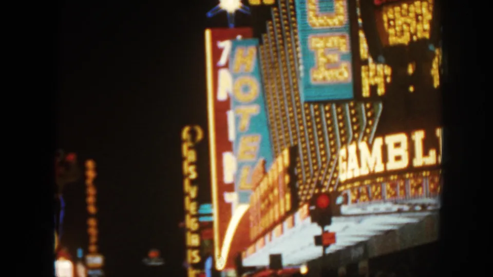 1962 8mm frame showing bright casino and hotel signage, marquee bulbs, and partial gambling lettering at night.