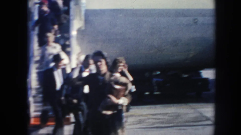 Travelers carrying bags move past the side of a Pan American plane in sunny 1962 Arizona home-movie footage.