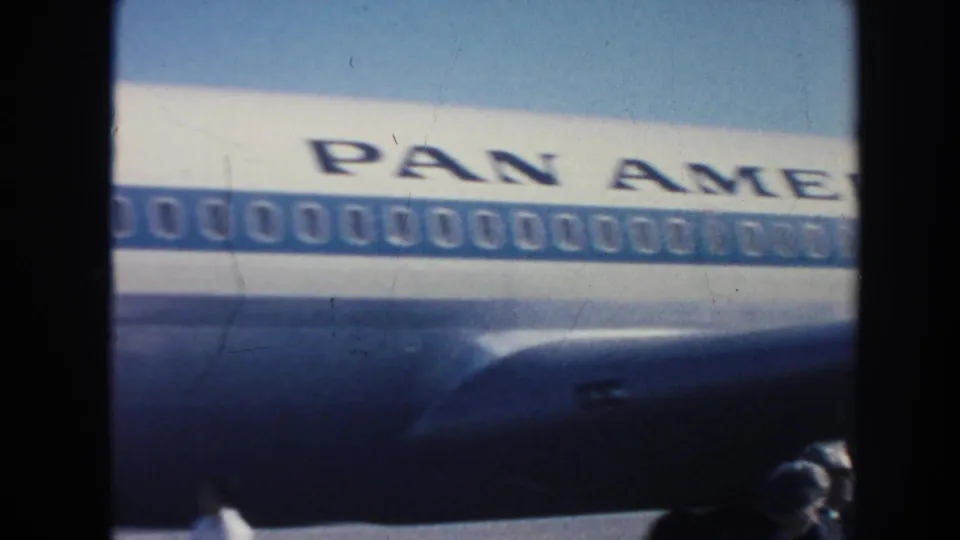 The Pan American name and rows of aircraft windows fill the frame, with travelers partly visible at the bottom edge.