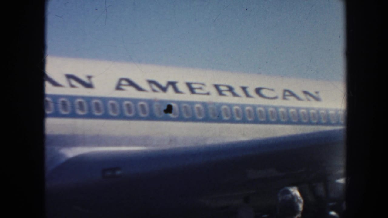 1962 home-movie frame showing a Pan American jet parked on a sunlit runway, with fuselage lettering and windows visible.