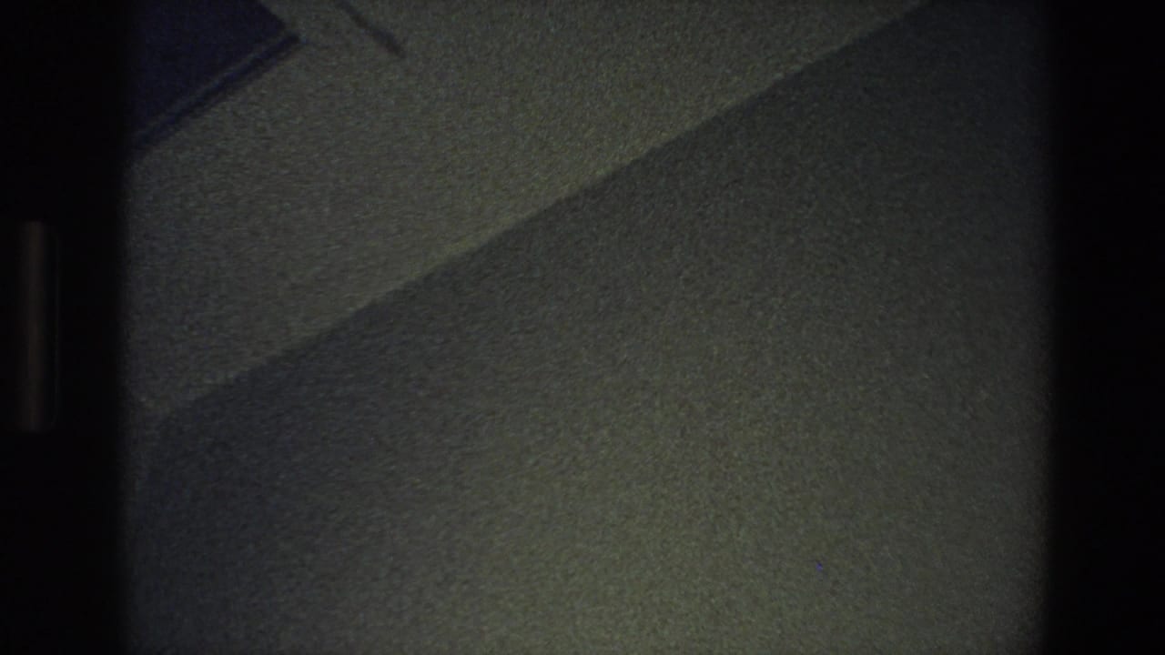 Dim textured wall with a diagonal shadow and dark vertical film borders.