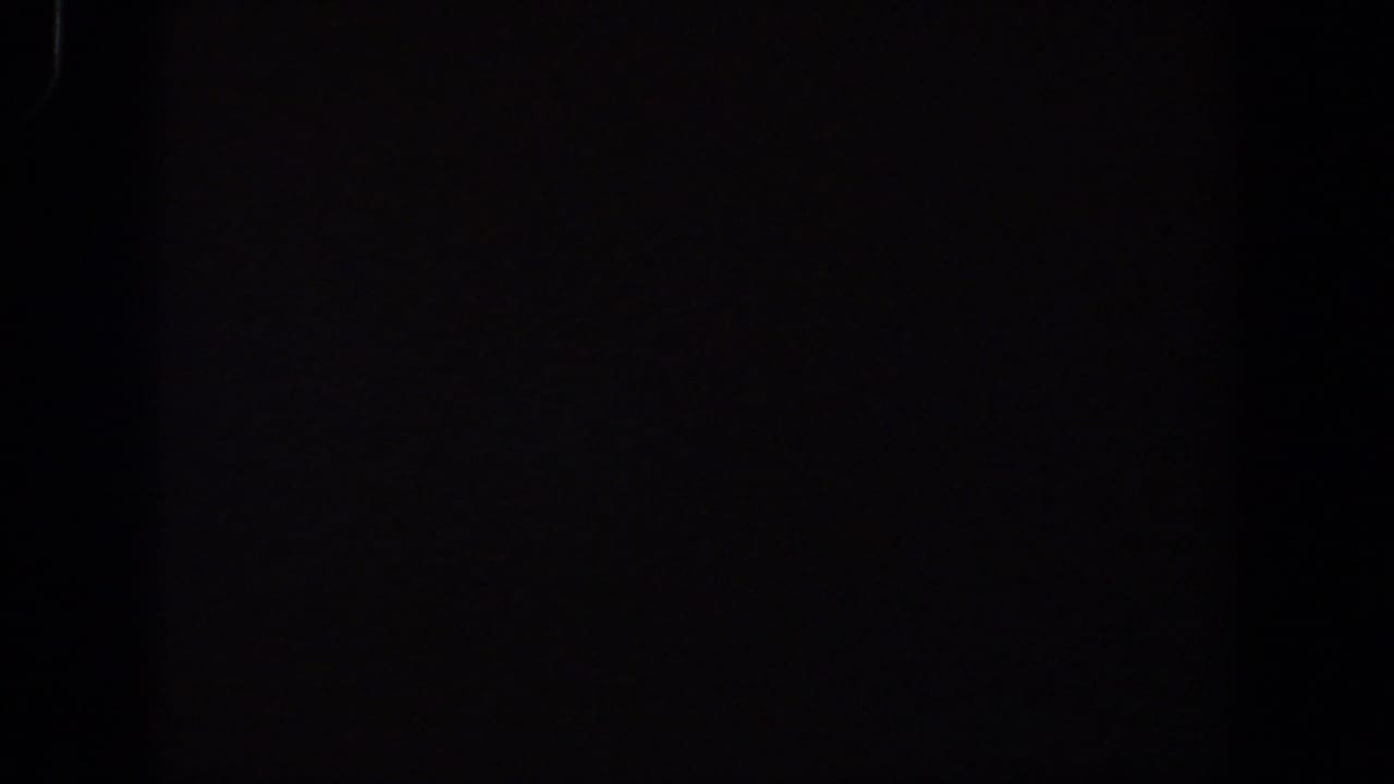 1958 Lubbock 8mm frame with a shadowed room area and faintly visible ledge or wall forms in very low light.
