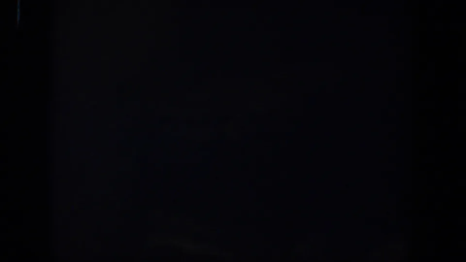 Black 8mm home-movie frame with subtle grain and no identifiable people, objects, or location detail.