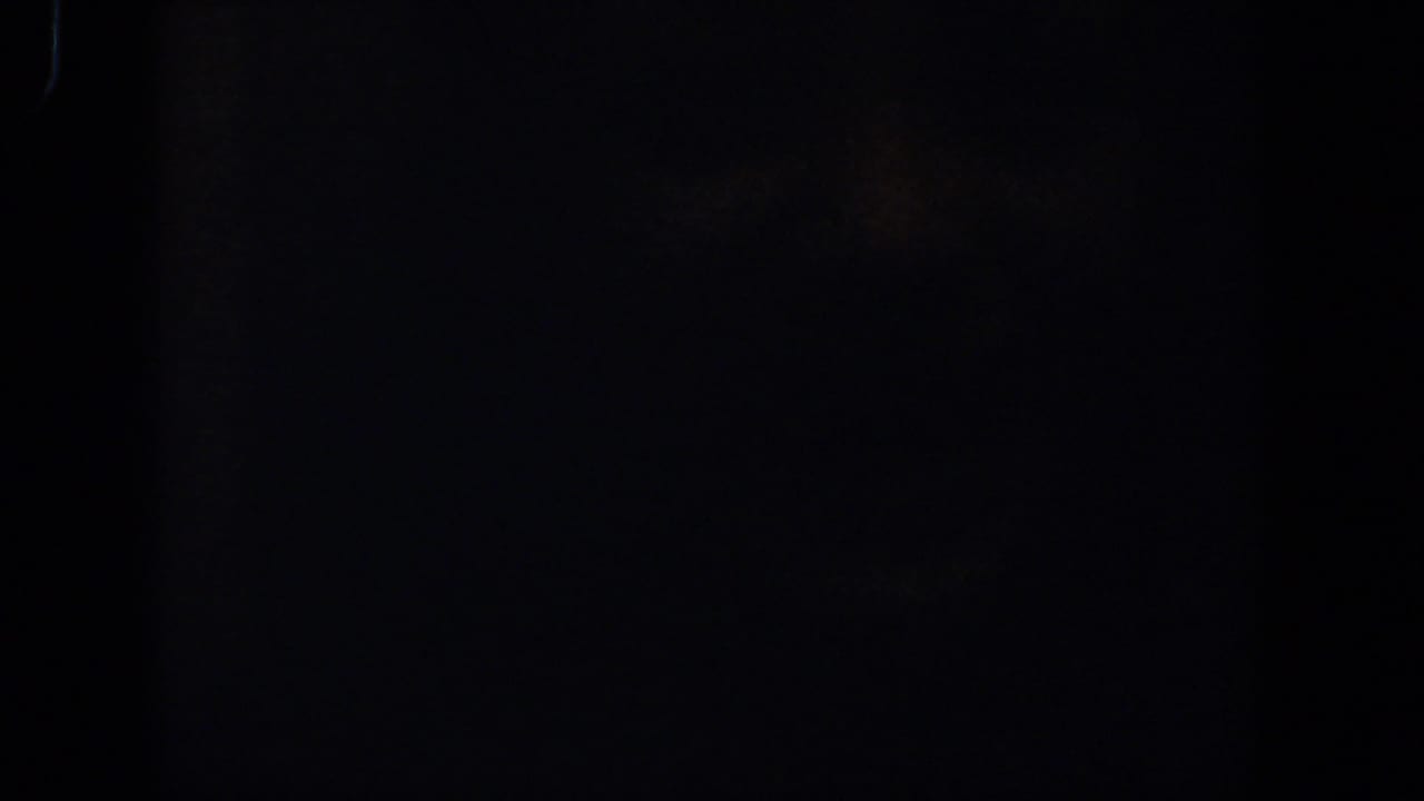 Nearly black frame with faint grain and a thin edge mark.
