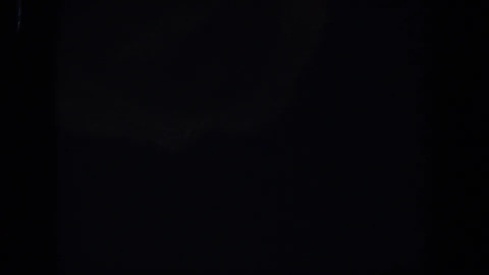 Very dark 1958 Lubbock 8mm home-movie frame with minimal visible detail, faint blue cast, and grain.
