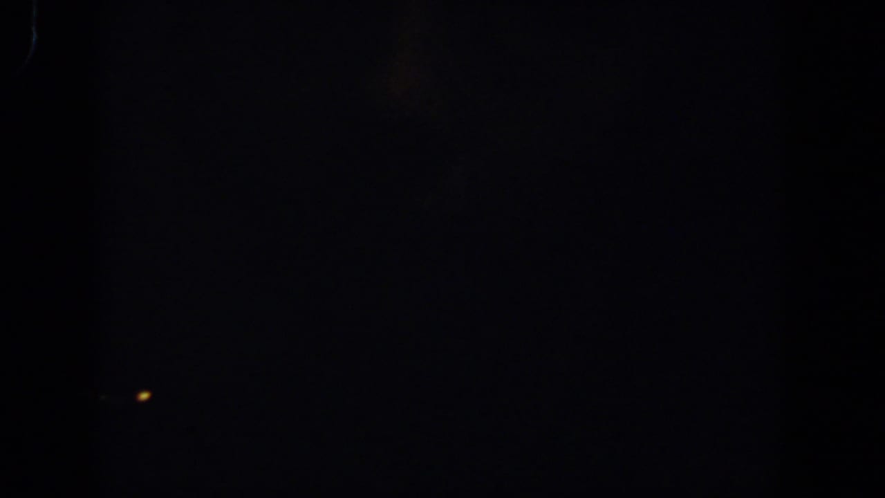 Dark frame with a small warm point of light near the center.