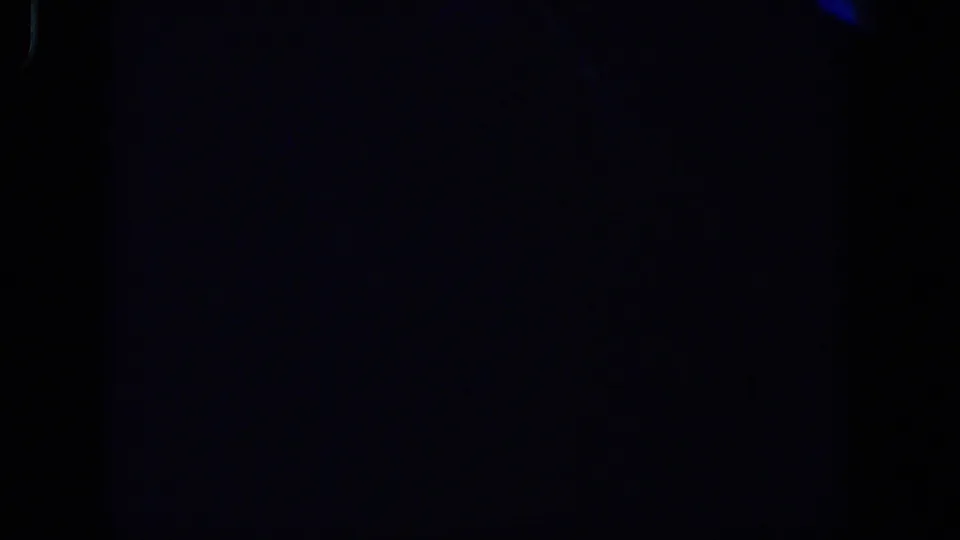 Very dark 1958 Lubbock 8mm home-movie frame with faint blue patches, grain, and edge darkness.