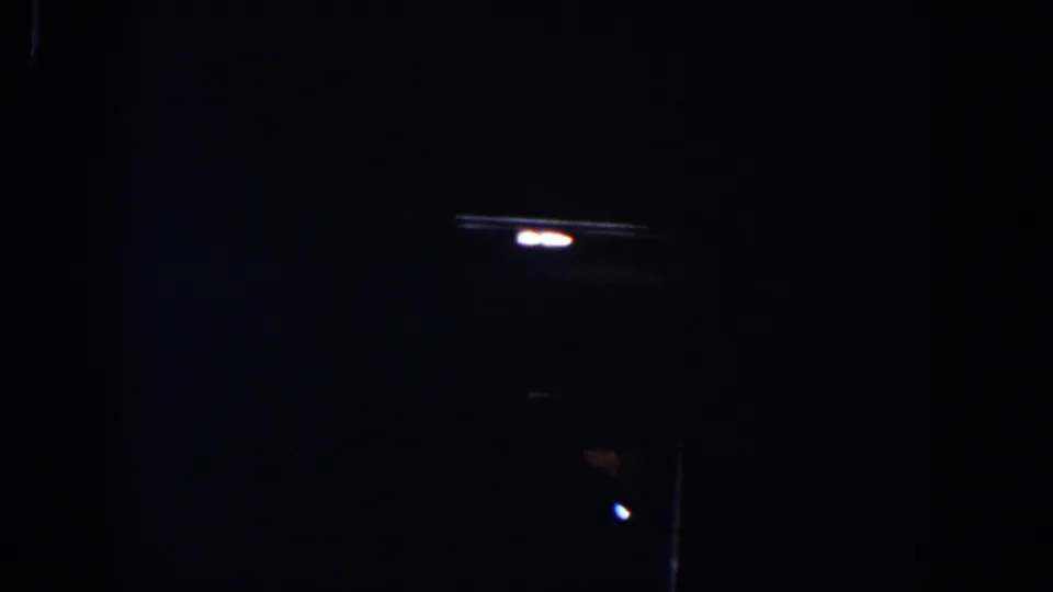 Very dark 1958 Lubbock home-movie frame with only small points of light and faint interior edges visible.