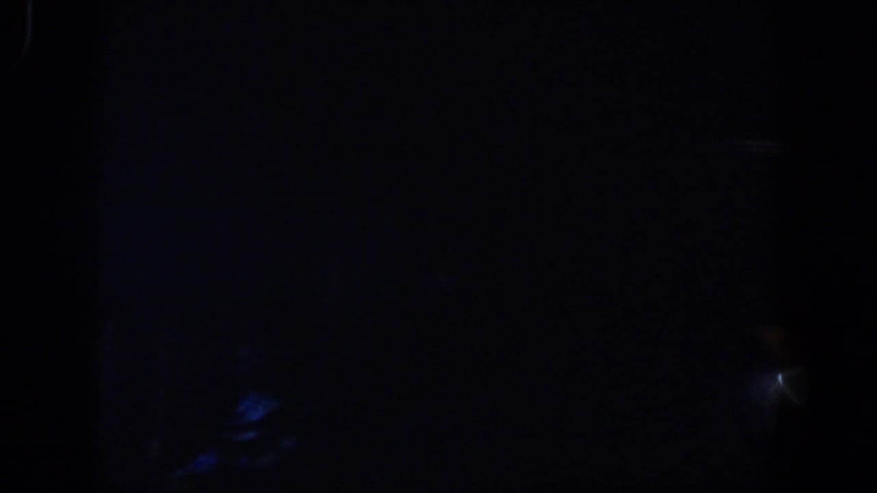 1958 8mm frame from Lubbock showing near-total darkness with faint cool blue streaks and soft film grain.