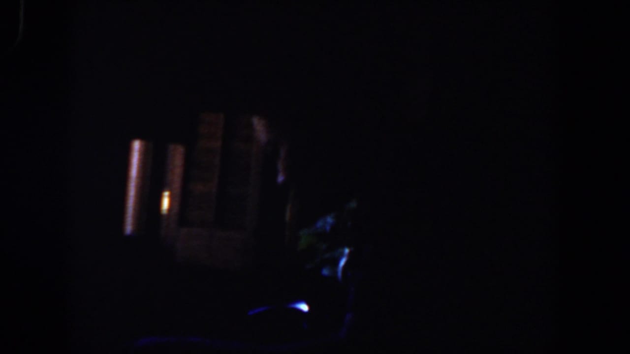 Dark interior frame with small warm lights and faint blue highlights.