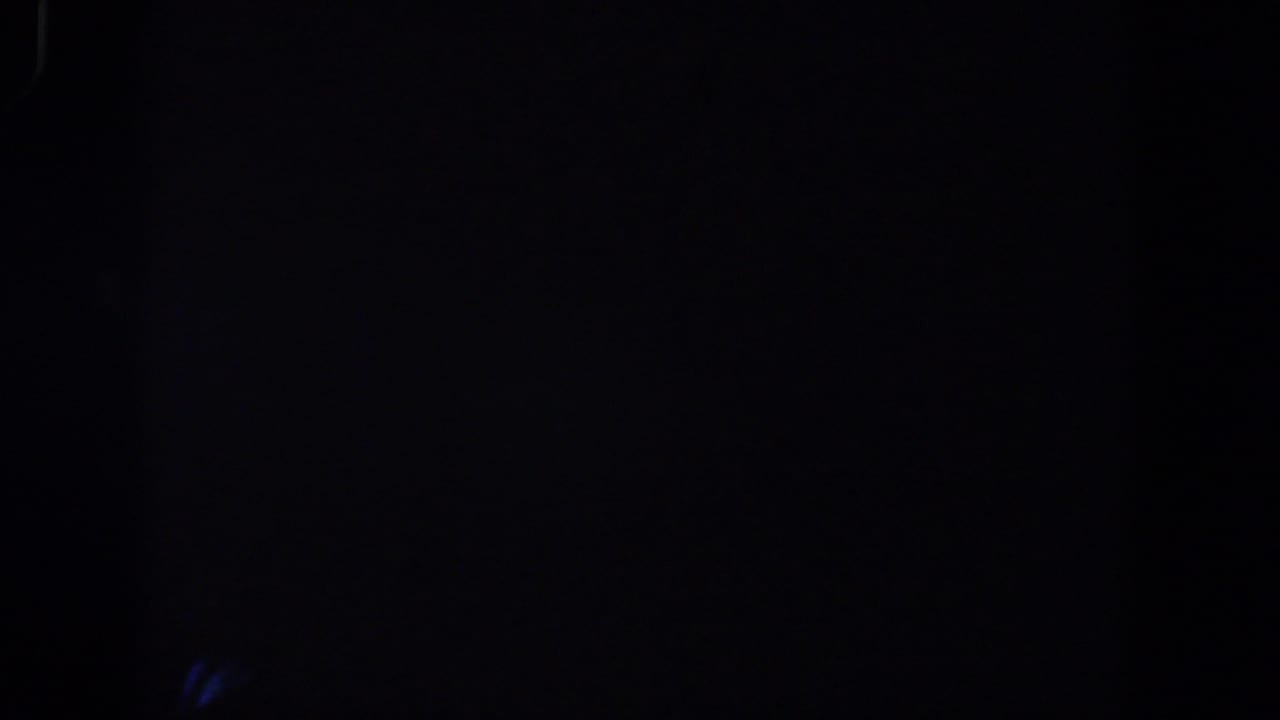 Very dark view through window framing with faint exterior lights.