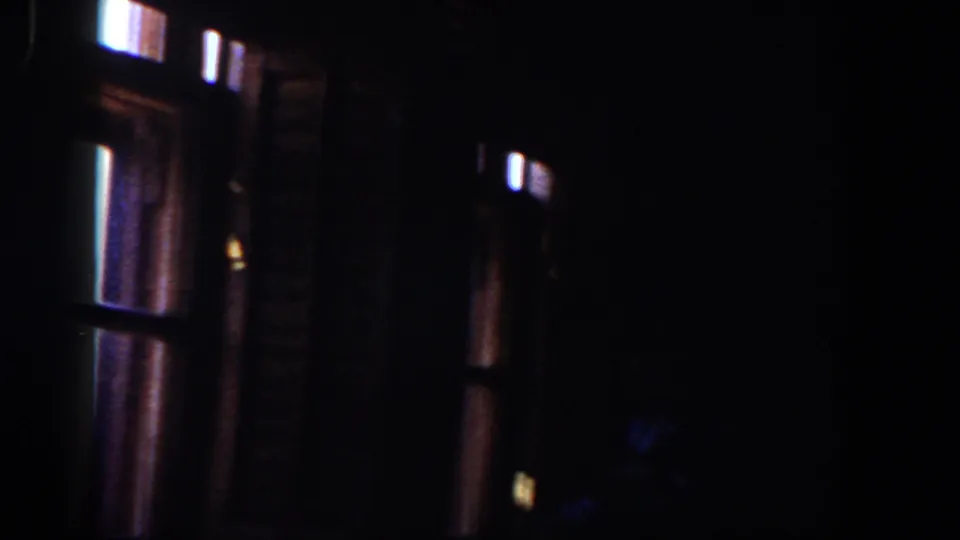 1958 Lubbock nighttime view from inside a dark room, with window frames and dim exterior lights visible.