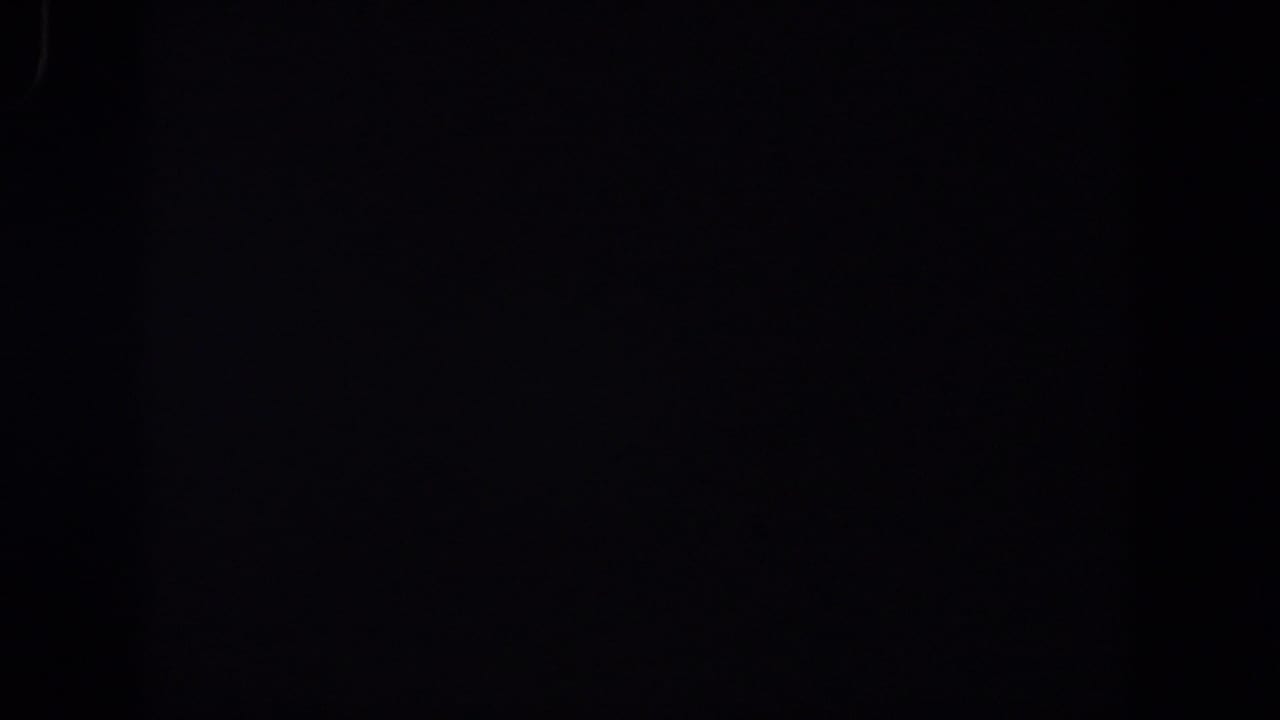 Dark 1958 8mm frame from the Lubbock reel with faint grain and almost no readable subject matter.