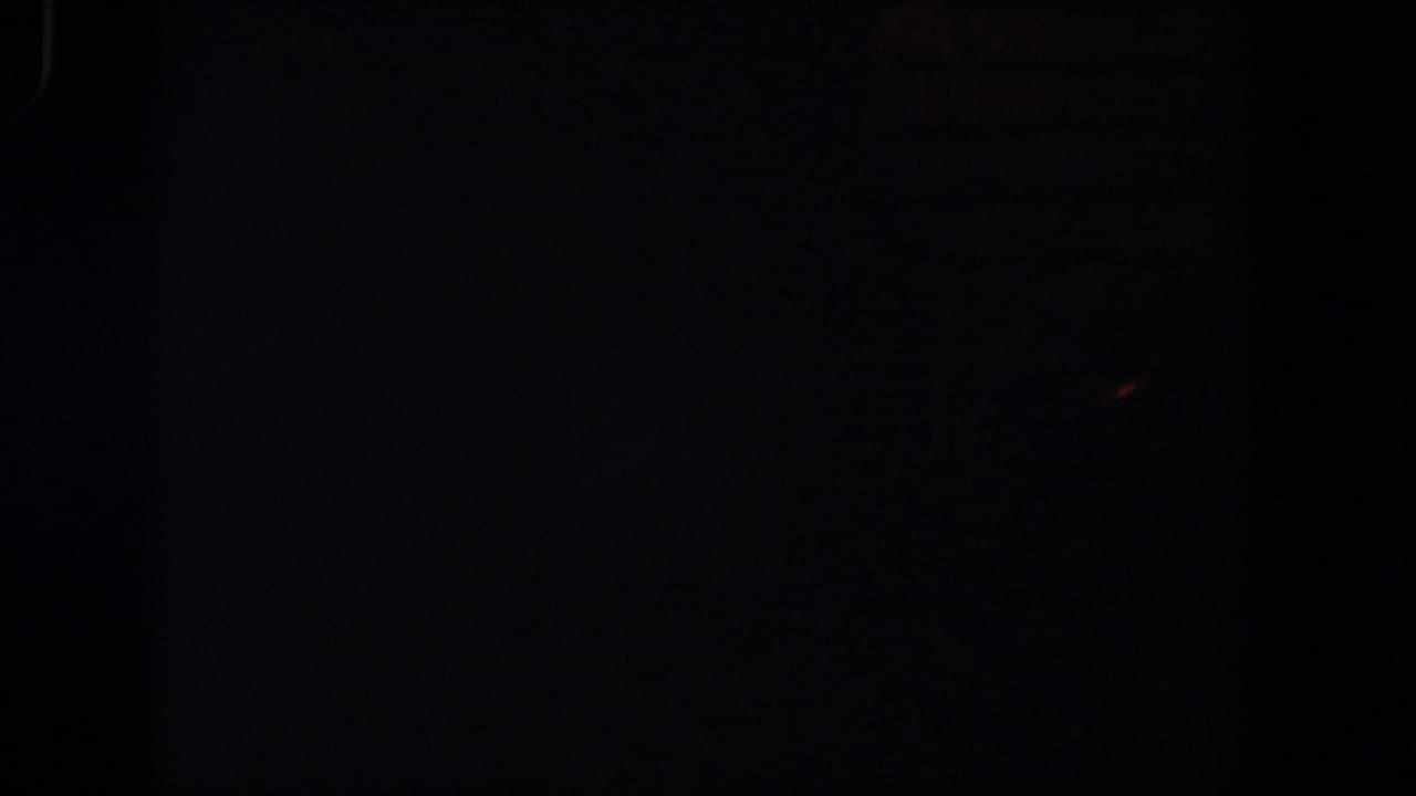 Nearly black frame with faint film texture and a dim warm speck near the upper right.