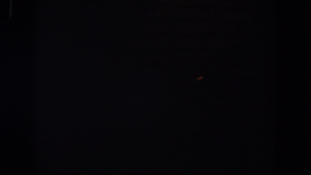 Mostly black frame with a tiny orange-red fleck near the upper right.