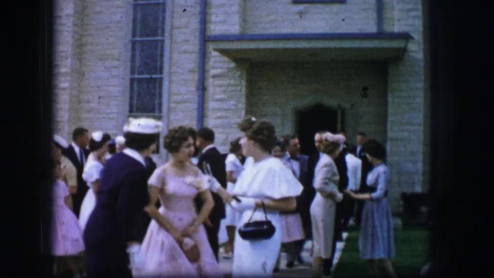 Women in formal attire converse outside a Moberly church in 1962, with suited men and other guests behind them.