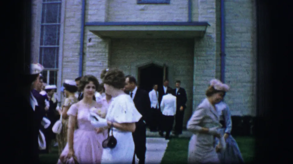 A formal church gathering in 1962 Moberly shows women in hats and dresses and suited men near the shaded doorway.