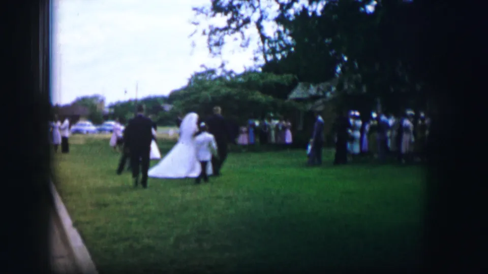 1962 Moberly garden wedding footage with the bride and companions moving across the lawn toward a group of guests.
