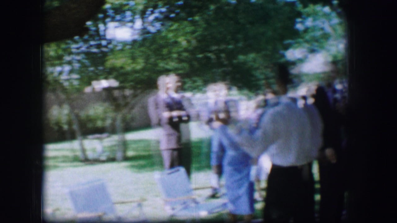 1962 Moberly, Missouri 8mm frame showing wedding guests on a lawn with chairs and trees in the background.