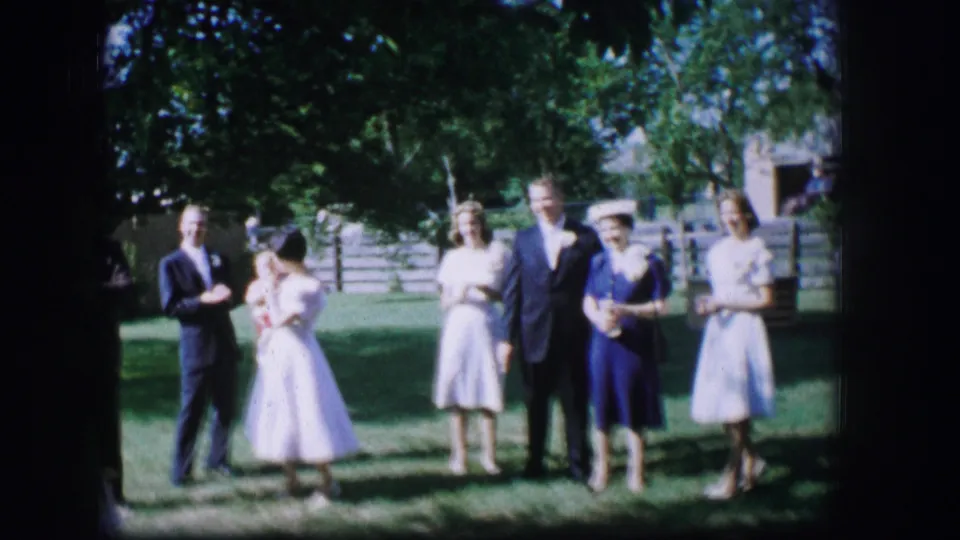 Wedding party in 1962 Moberly, Missouri posed outside with trees and a fence behind them.