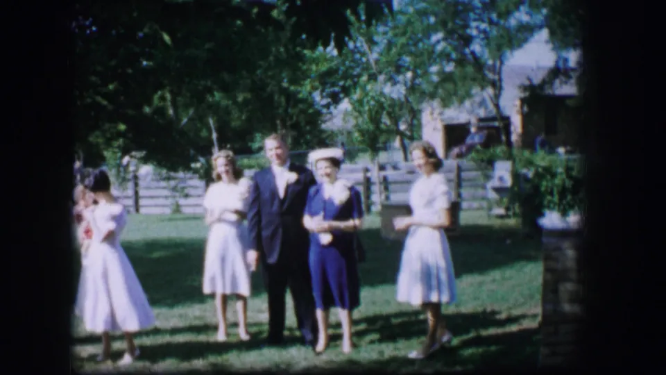 Outdoor 1962 Missouri wedding scene with the groom and attendants standing near the bride at frame edge.