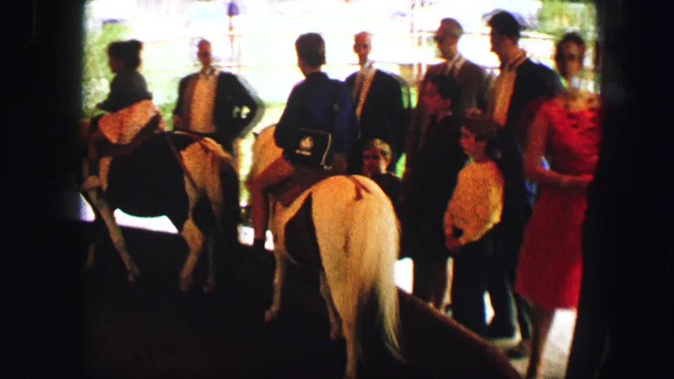 Children ride small horses as adults and attendants stand nearby in an Austria 1963 outdoor attraction scene.