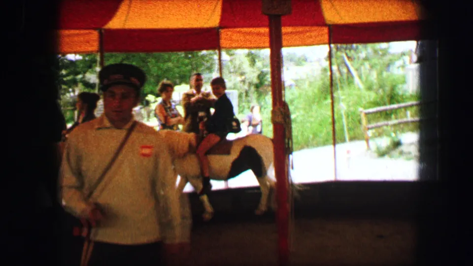 A uniformed attendant stands near a small horse with a child rider beneath a striped canopy in the Austria 1963 home movie.