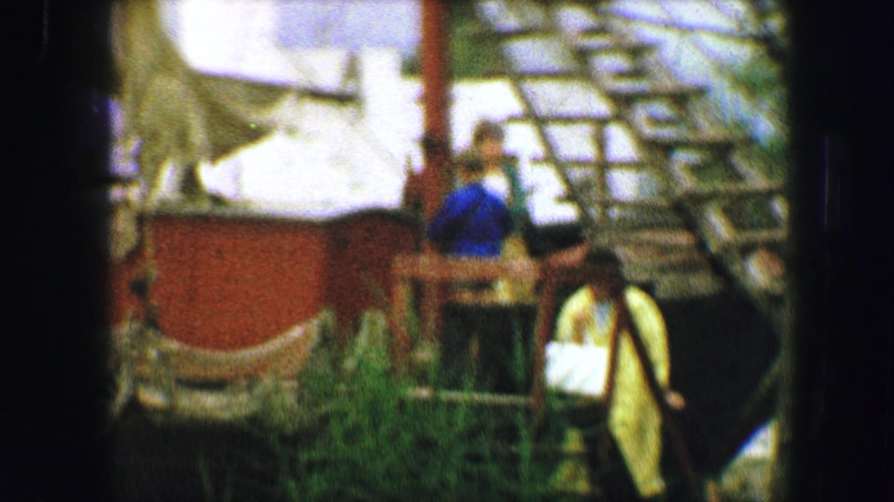 Austria 1963 home-movie frame showing people near an outdoor airport-area structure, with soft focus and heavy film grain.