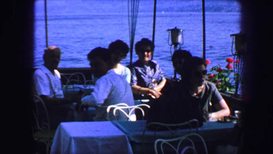 1963 Lucerne dining room view with patrons seated by large windows, flower boxes, and blue water beyond.