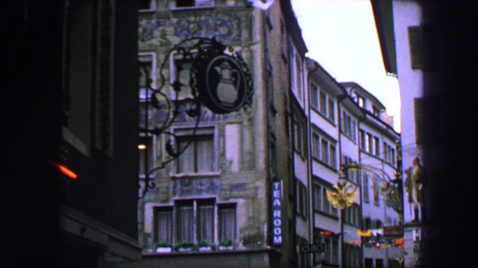 Lucerne old-town facades in 1963, with hanging signs, flags, hotel lettering, windows, and a partially framed street view.