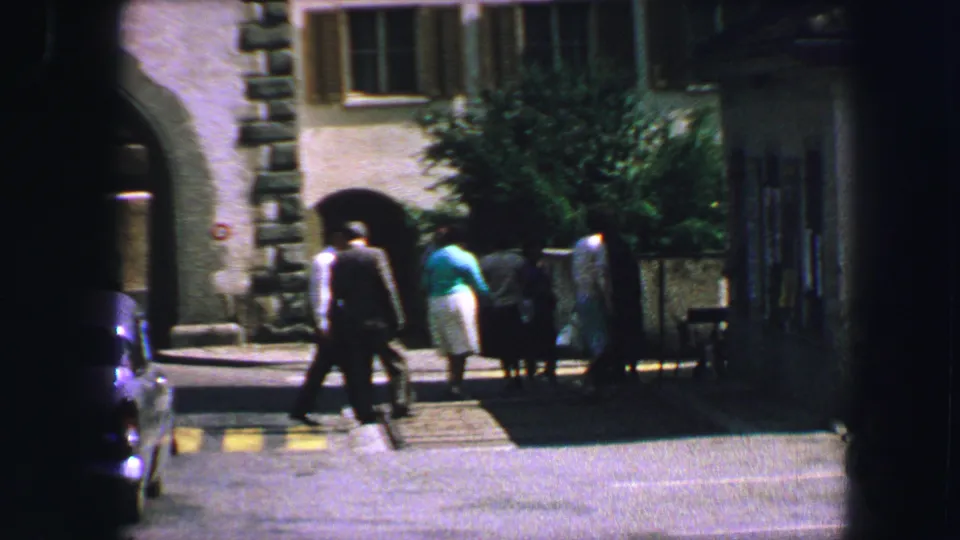 A 1963 Lucerne street moment shows pedestrians crossing beside arched stone architecture and a shaded walkway.