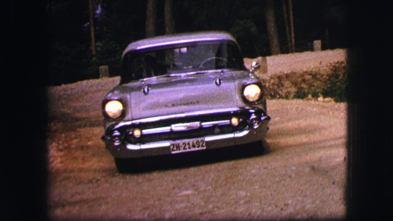 1963 Saint Moritz home-movie frame showing a silver Chevrolet Bel Air approaching the camera on a roadside curve.