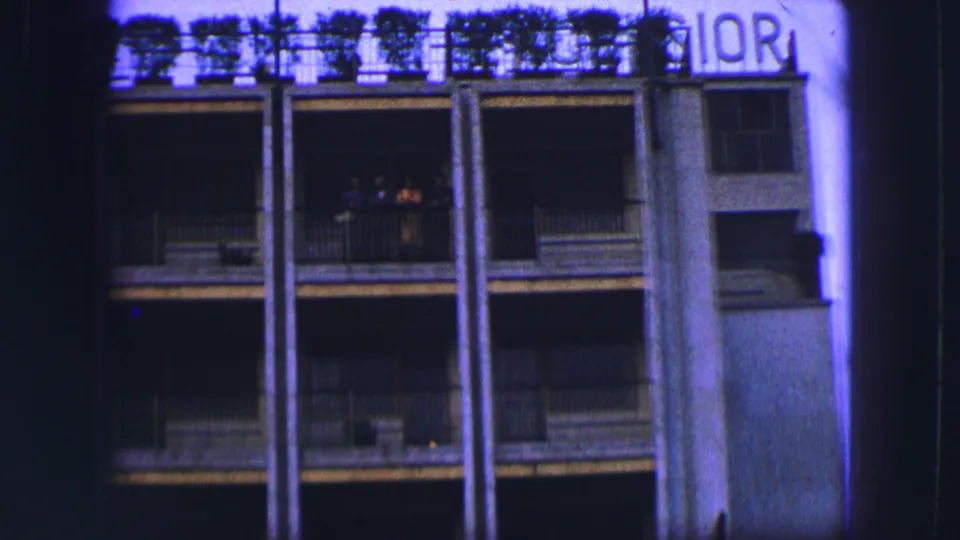 1963 Saint Moritz home-movie view of a multi-story balcony facade with columns, railings, and partial roof lettering.