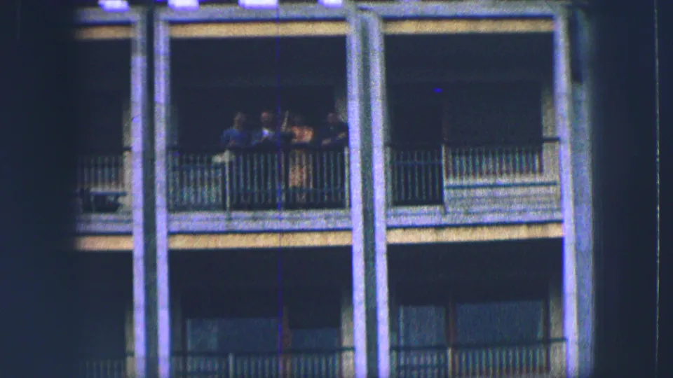 Four people stand on a balcony of a yellow-gray building in Saint Moritz, seen in soft 1963 8mm footage.