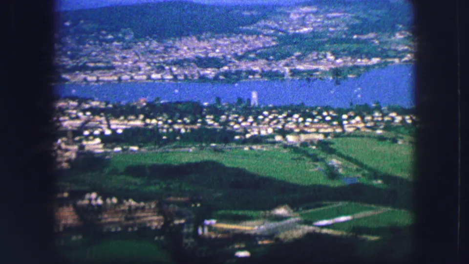 A wide Saint Moritz view shows the lake, hillside settlement, green fields, and distant slopes in soft vintage 8mm color.