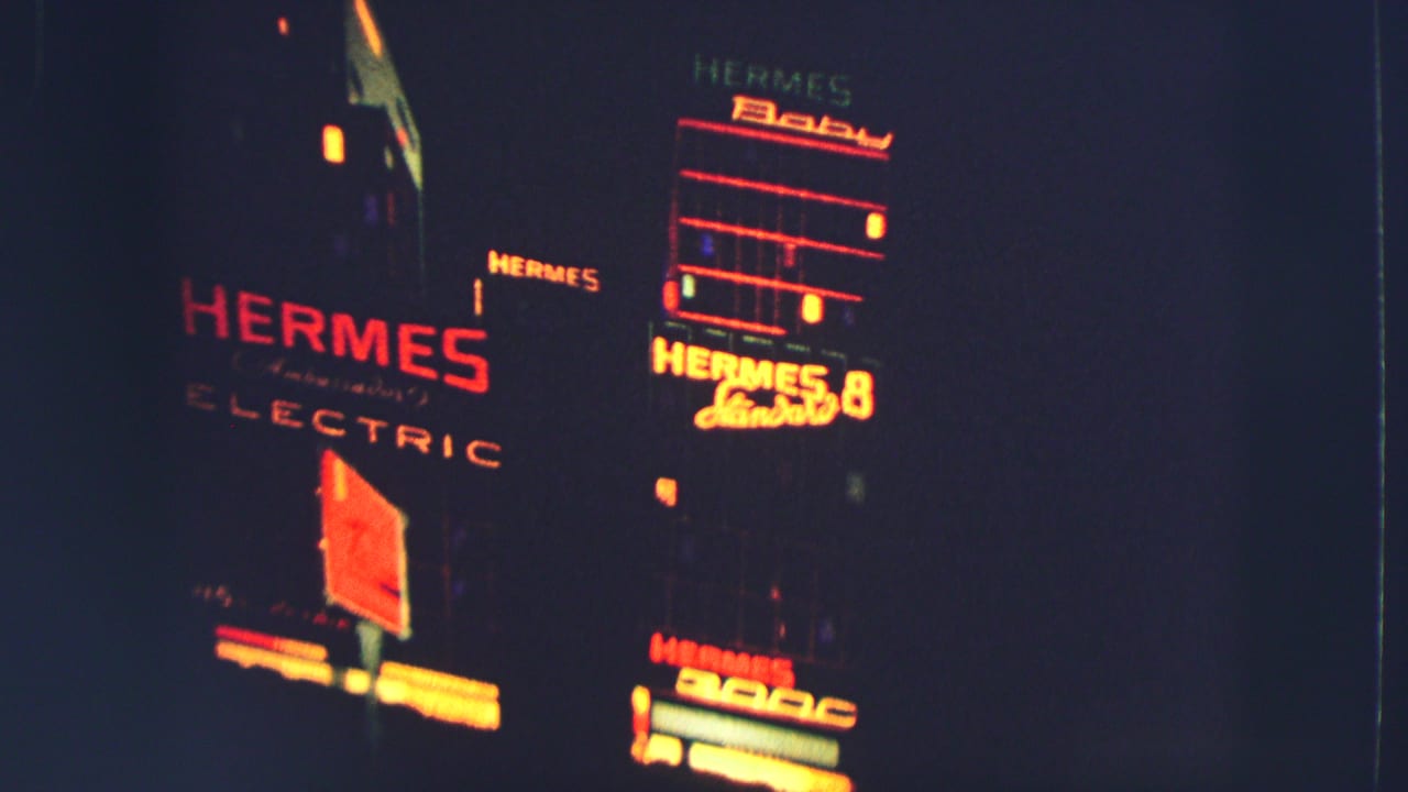 Dark nighttime street view with illuminated Hermes Electric and Hermes Baby signs.