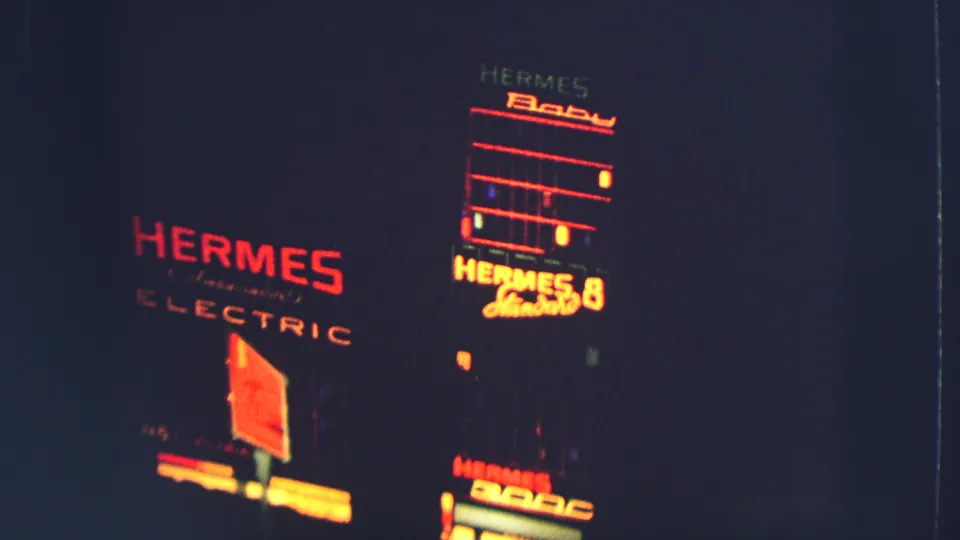 1963 Zurich night frame with Hermes Electric lettering and a bright Hermes Baby sign visible on shadowed building fronts.