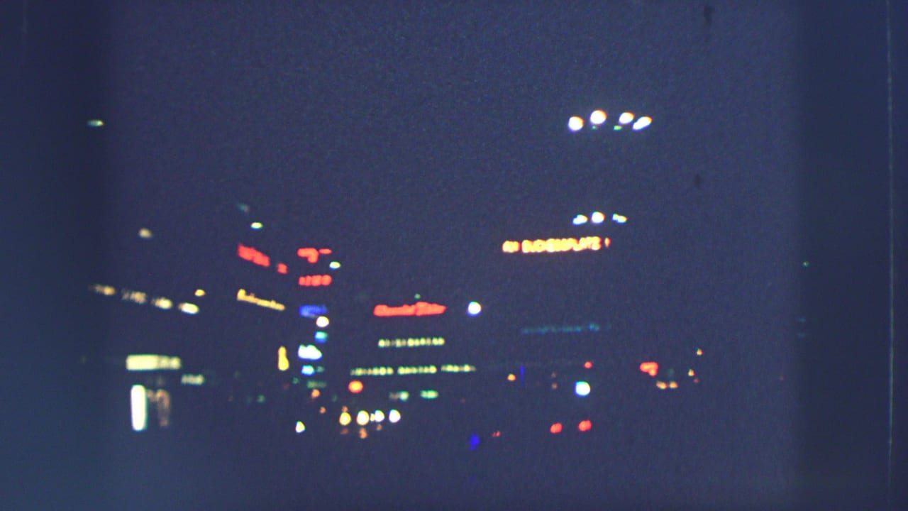 Night street scene with distant neon-like lights and dark roadway.