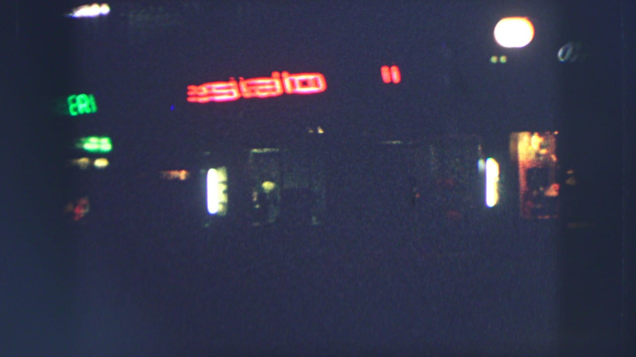 Dark Zurich street scene with blurred red and green neon signs.