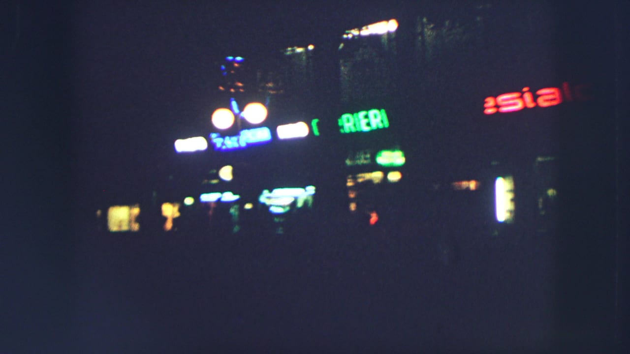 Night street view with bright lamps and colored illuminated signs.