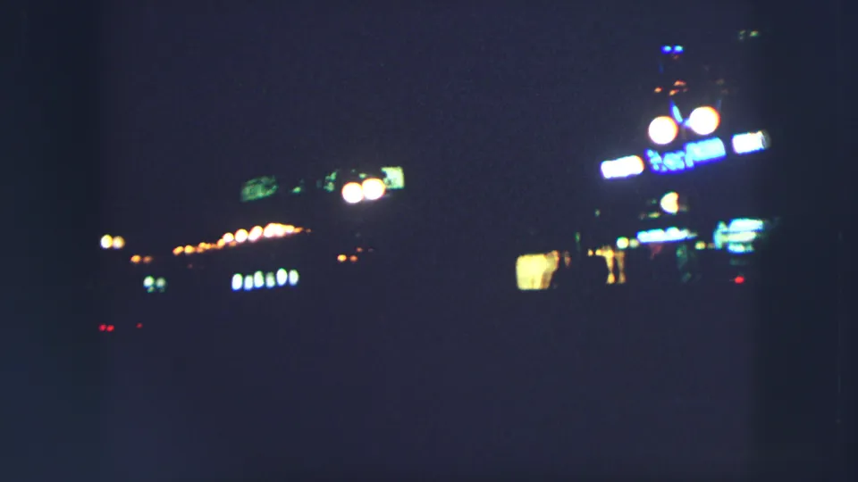 A dim Zurich night view from 1963 shows rows of small street lights and a bright sign receding into darkness.