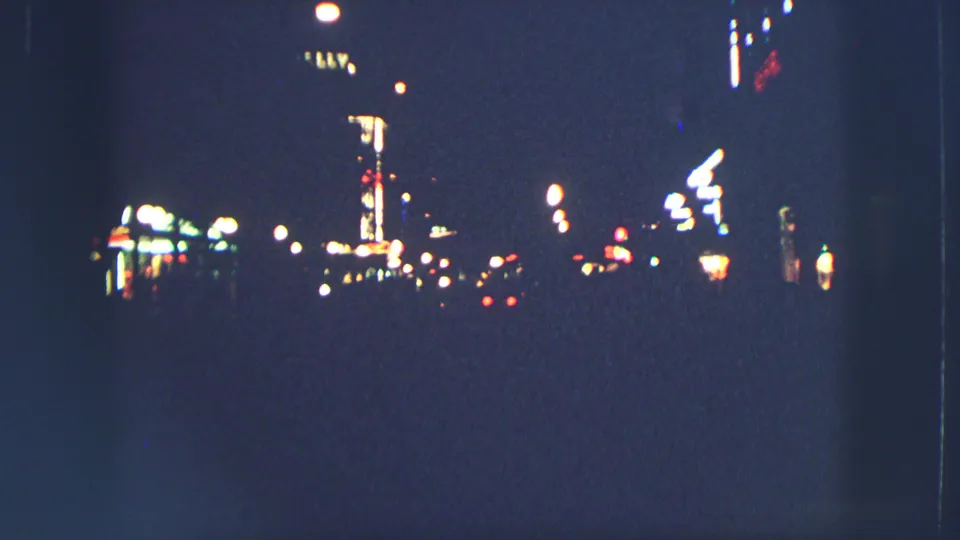 1963 Zurich night street seen from a distance, with soft neon glows and street lamps against a dark urban background.