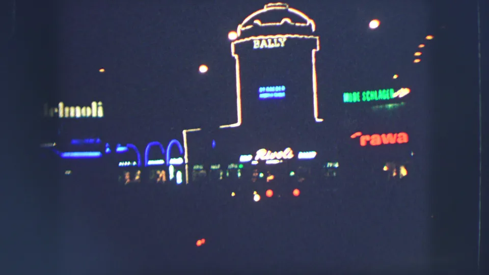 Zurich night storefronts in 1963, with a prominent Bally sign and multiple glowing commercial signs across the street.