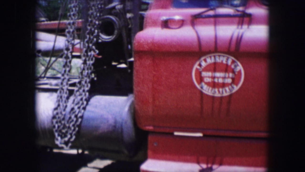 Red truck cab side with chains, tank, tire edge, and painted door lettering.
