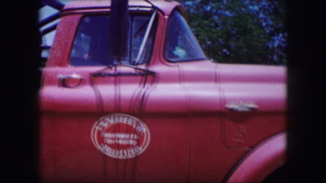 Close view of a red utility truck cab in Dallas, Texas, 1964, with a circular logo on the door and chrome trim visible.