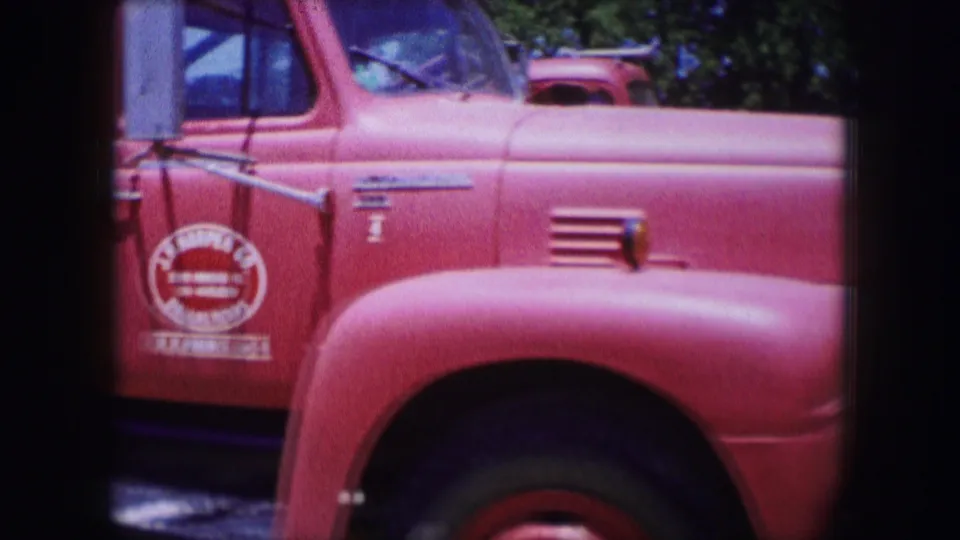 1964 Dallas 8mm frame showing a red work truck in close-up, with chrome trim, side mirror, rounded fender, and partial painted lettering.